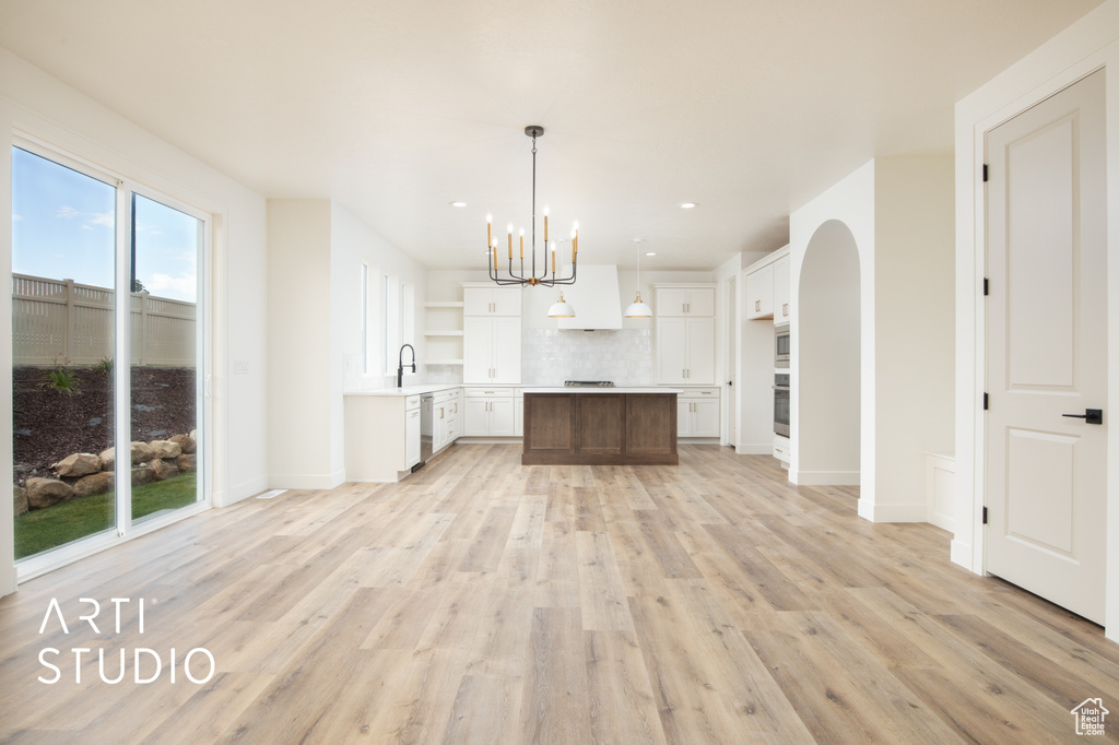 Kitchen with a center island, a healthy amount of sunlight, light wood-type flooring, and hanging light fixtures