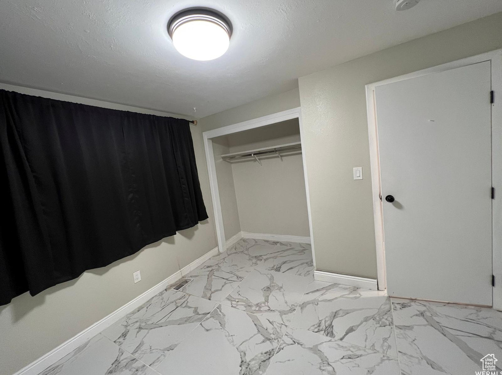 Unfurnished bedroom featuring a textured ceiling and a closet