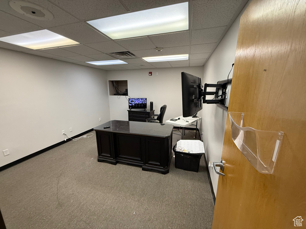 Carpeted home office with baseboards, visible vents, and a drop ceiling