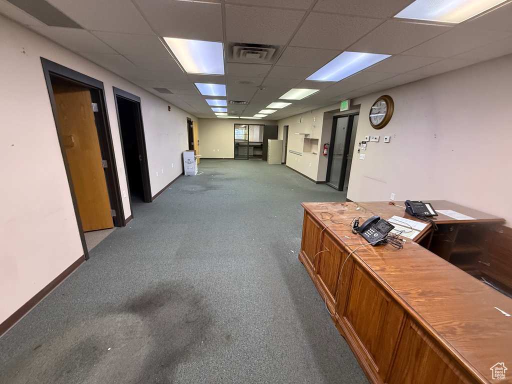 Hall featuring a paneled ceiling, carpet flooring, visible vents, and baseboards