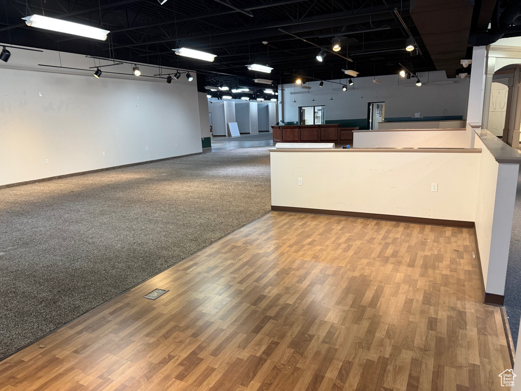 Interior space with rail lighting, open floor plan, baseboards, and wood finished floors