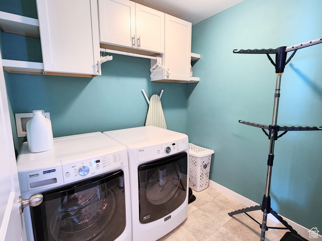 Laundry area featuring washing machine and clothes dryer, cabinets, and light tile patterned floors