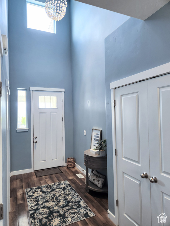 Foyer entrance featuring dark wood-type flooring, an inviting chandelier, and a towering ceiling