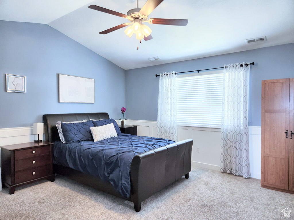 Bedroom with light colored carpet, ceiling fan, and vaulted ceiling