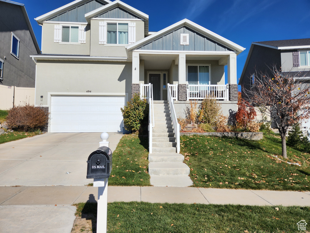 Craftsman-style home featuring a front yard, a garage, and a porch