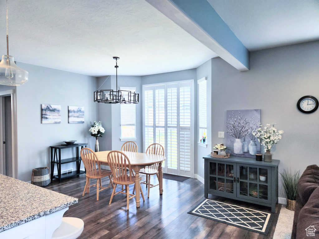 Dining area featuring a chandelier, dark hardwood / wood-style flooring, beamed ceiling, and a textured ceiling