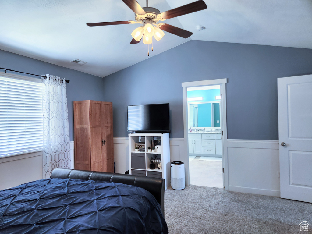 Carpeted bedroom with ceiling fan, ensuite bathroom, and vaulted ceiling