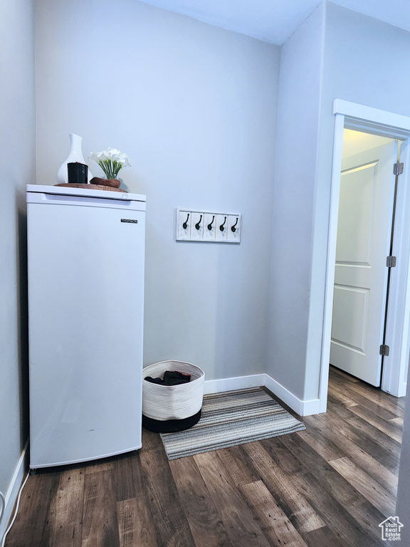 Clothes washing area with dark hardwood / wood-style flooring