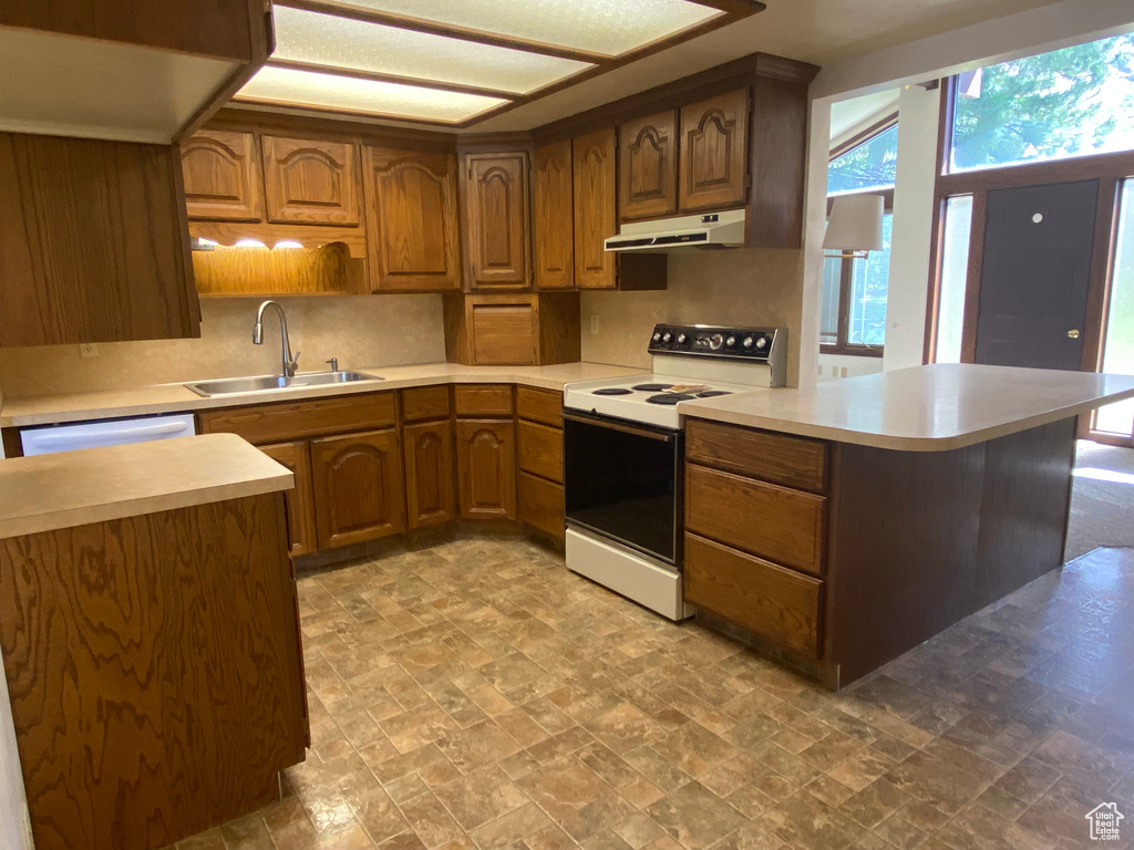 Kitchen with white appliances, backsplash, kitchen peninsula, and sink