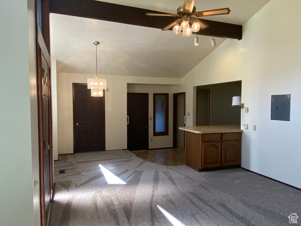 Kitchen with ceiling fan with notable chandelier, kitchen peninsula, lofted ceiling with beams, electric panel, and carpet flooring