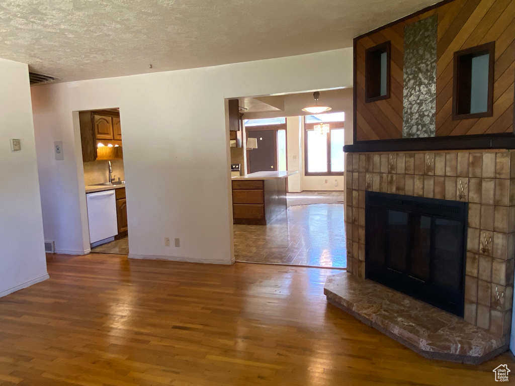 Unfurnished living room with a textured ceiling, hardwood / wood-style flooring, and wooden walls