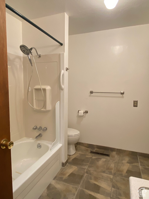 Bathroom with toilet, tile patterned floors, and washtub / shower combination