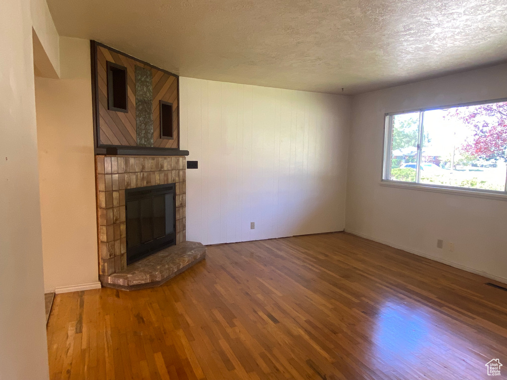 Unfurnished living room with a textured ceiling, wood-type flooring, and a fireplace