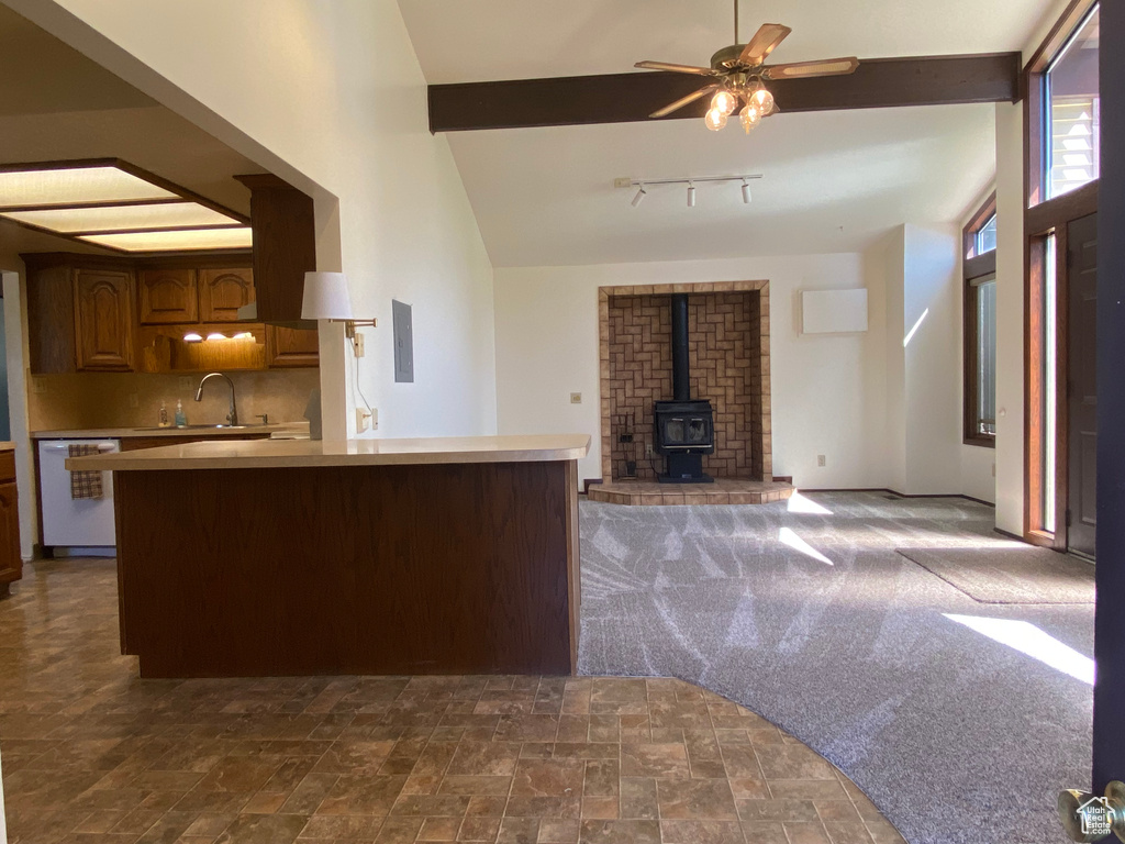 Kitchen featuring dark carpet, a wood stove, dishwasher, backsplash, and ceiling fan