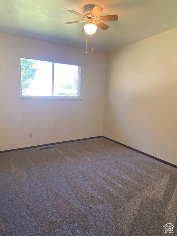 Carpeted empty room featuring ceiling fan