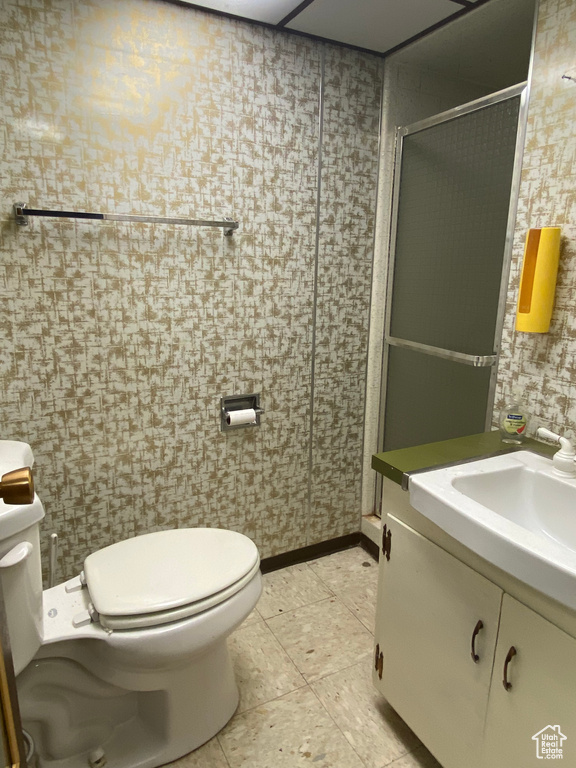 Bathroom featuring tile patterned flooring, walk in shower, toilet, and vanity