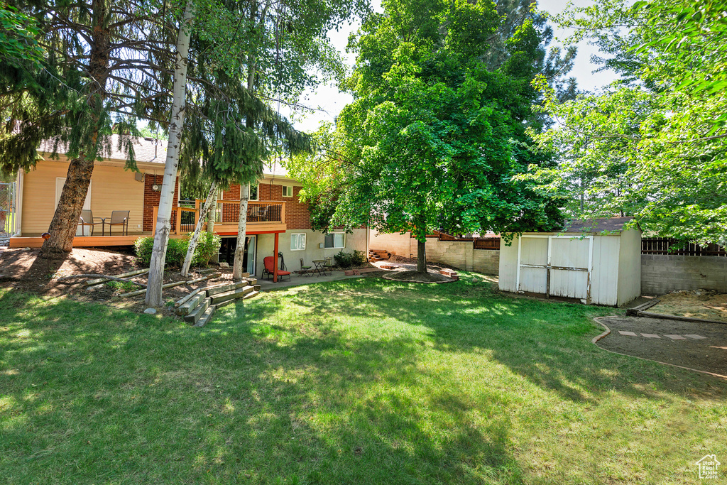 View of yard featuring a storage unit and a deck