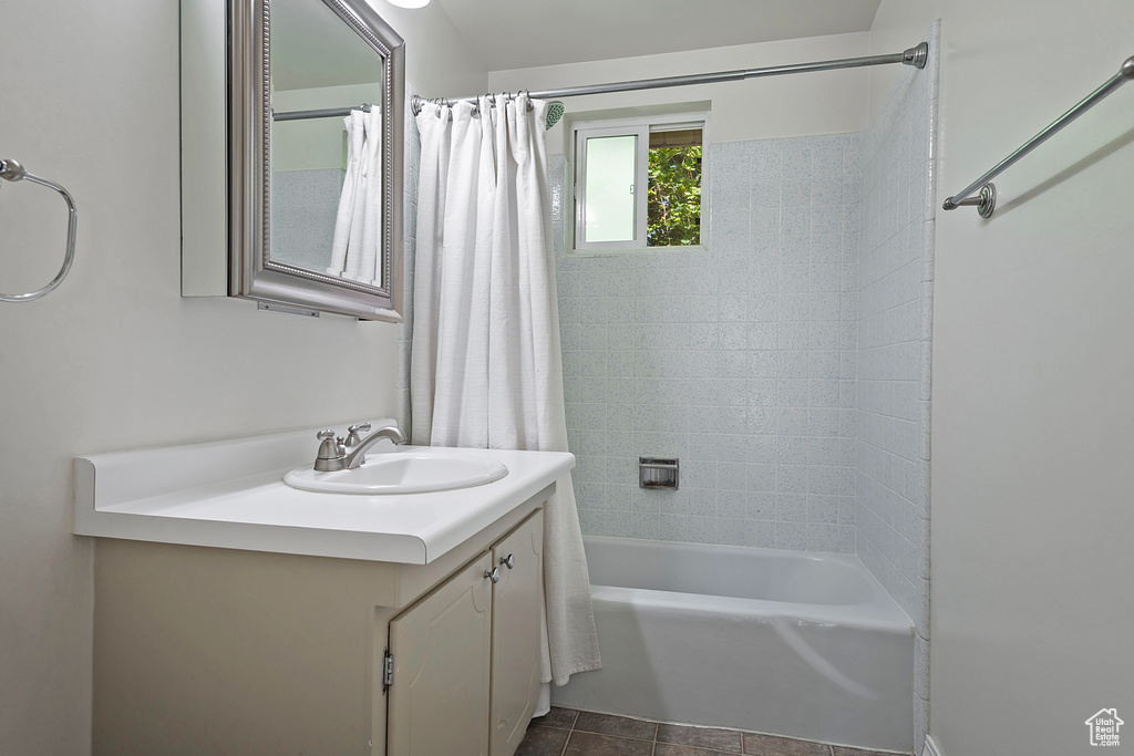 Bathroom featuring tile patterned flooring, shower / bathtub combination with curtain, and vanity