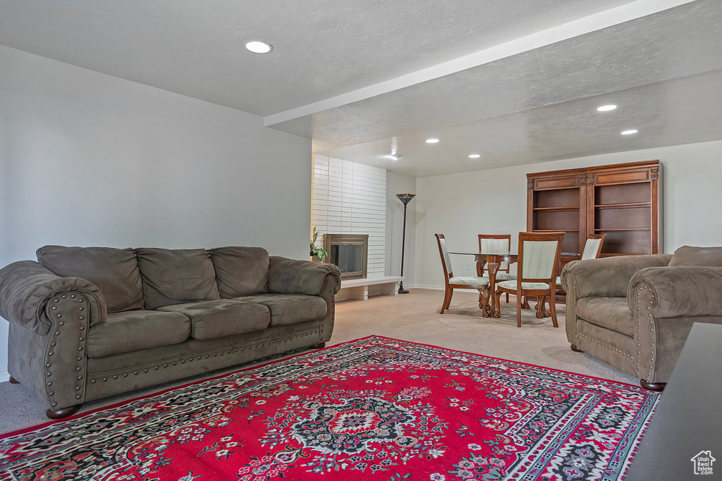 Carpeted living room with a textured ceiling and a brick fireplace