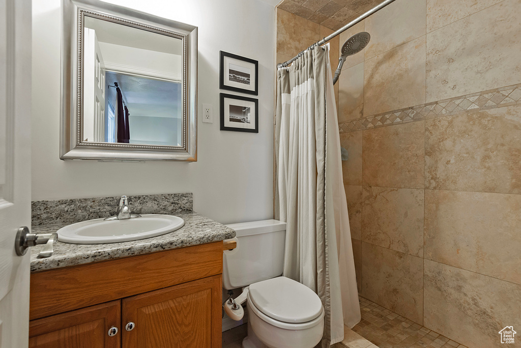 Bathroom with a shower with shower curtain, toilet, and vanity