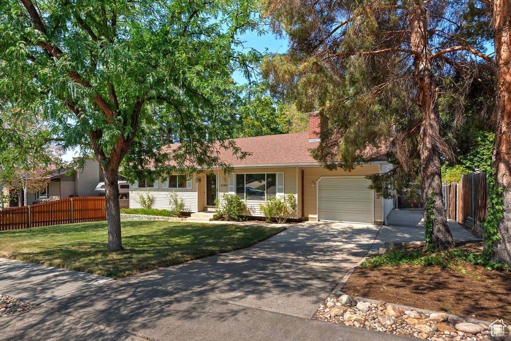 Ranch-style home featuring a garage and a front lawn