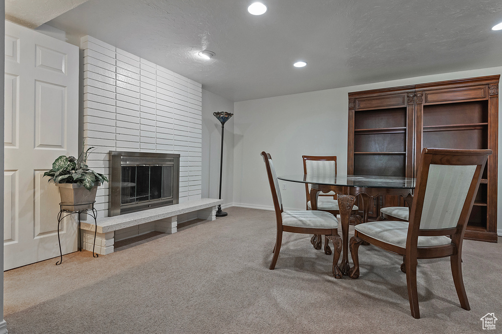 Carpeted dining room with a textured ceiling and a large fireplace