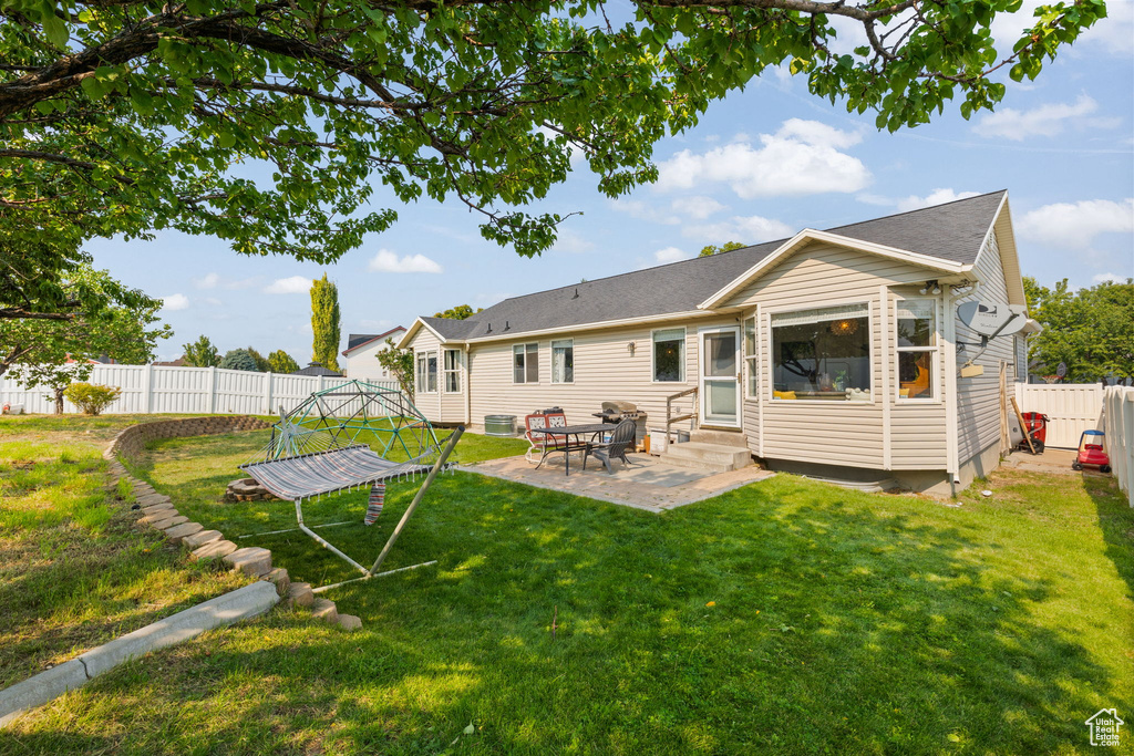 Rear view of house with a patio area and a lawn