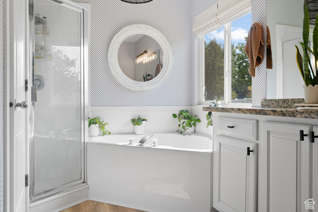 Bathroom featuring hardwood / wood-style floors, separate shower and tub, and vanity