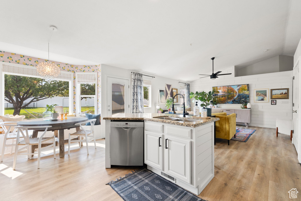 Kitchen featuring vaulted ceiling, ceiling fan with notable chandelier, white cabinetry, sink, and stainless steel dishwasher