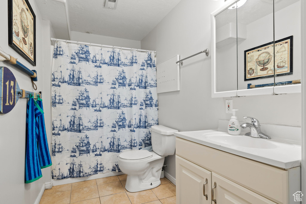 Bathroom featuring tile patterned floors, walk in shower, toilet, and vanity