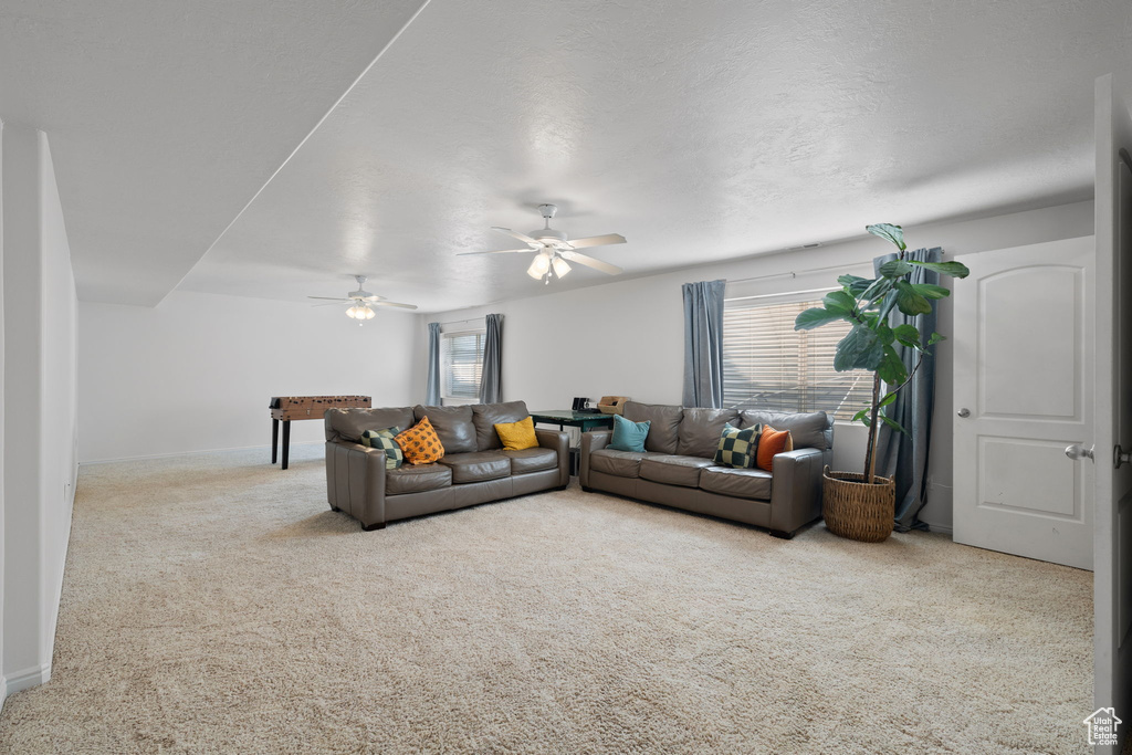 Living room featuring ceiling fan, a textured ceiling, and carpet floors