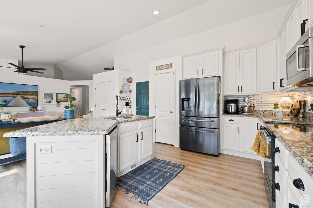 Kitchen featuring white cabinets, appliances with stainless steel finishes, ceiling fan, and vaulted ceiling