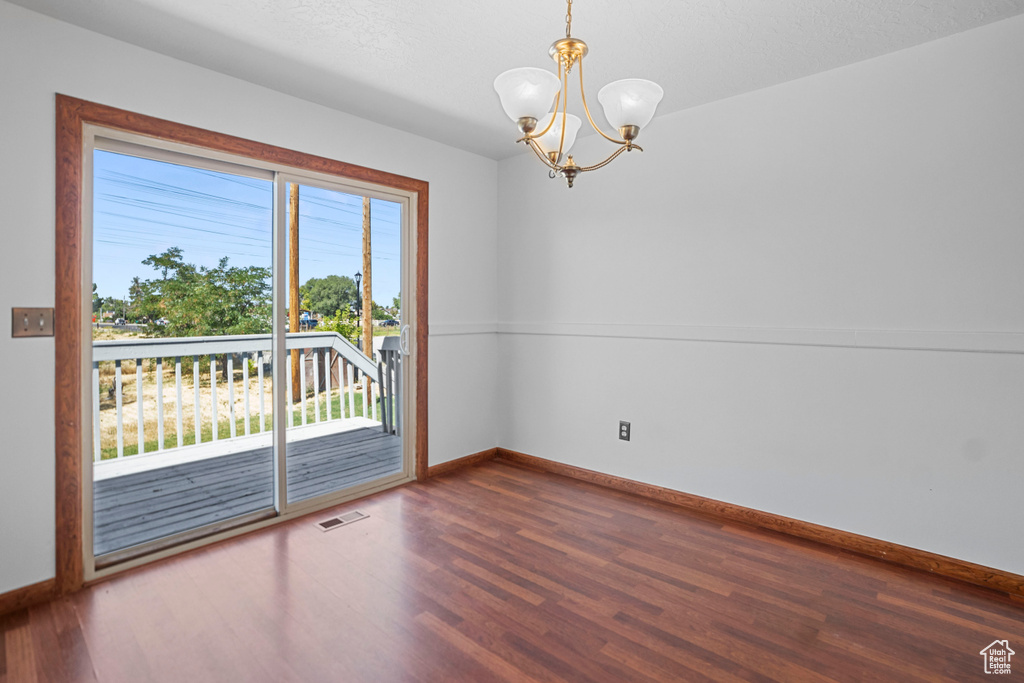 Unfurnished room featuring dark wood-type flooring and a chandelier