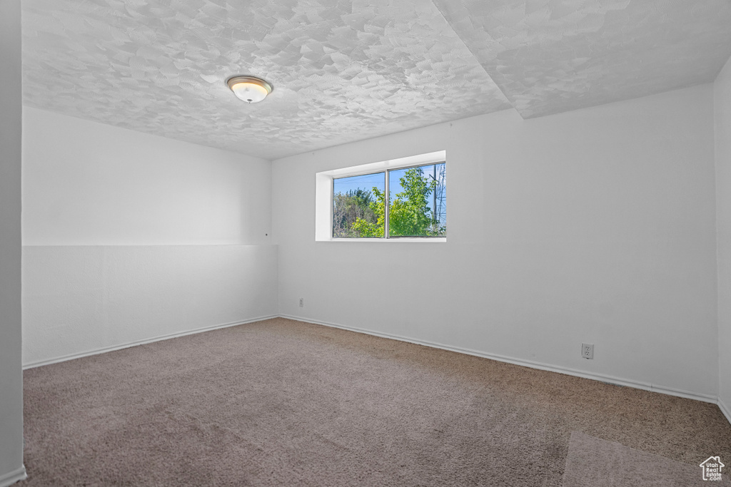 Carpeted spare room featuring a textured ceiling