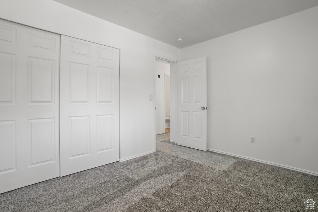 Unfurnished bedroom with light colored carpet and a closet