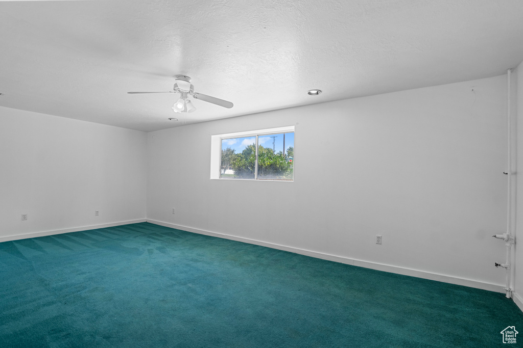 Carpeted empty room with a textured ceiling and ceiling fan