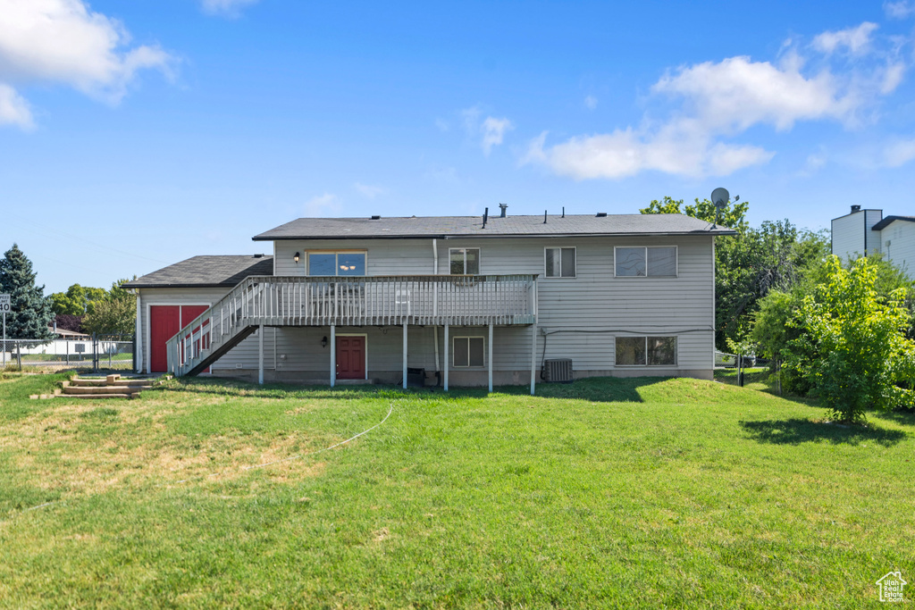 Back of property featuring a wooden deck and a lawn