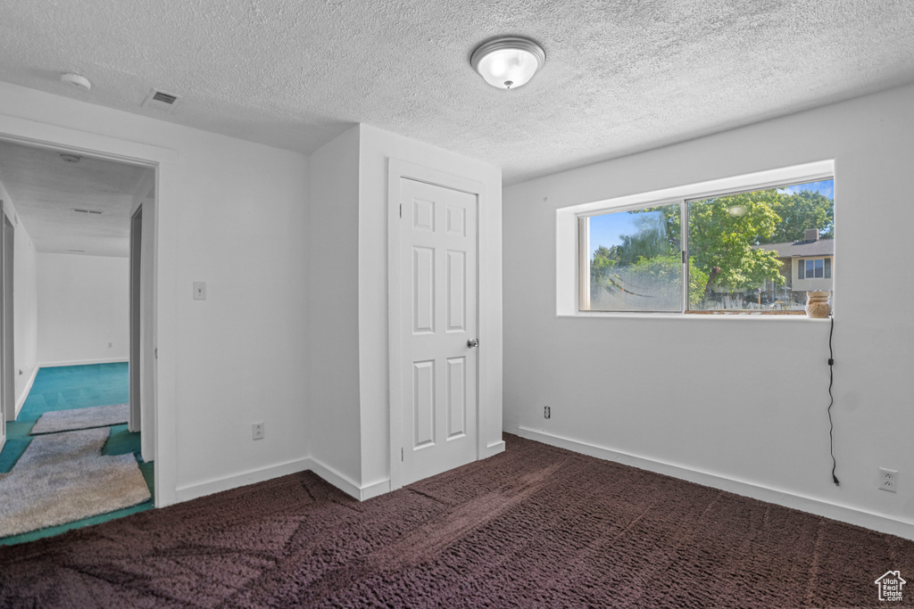 Unfurnished bedroom with a closet, carpet, and a textured ceiling