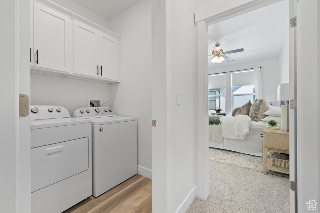 Laundry room with light hardwood / wood-style flooring, cabinets, washing machine and dryer, and ceiling fan