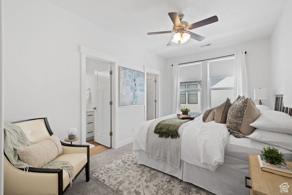 Bedroom with light hardwood / wood-style flooring, ceiling fan, and ensuite bathroom