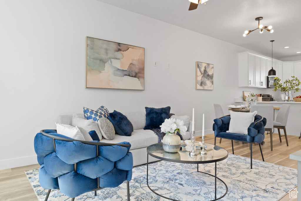 Living room featuring light wood-type flooring and ceiling fan with notable chandelier