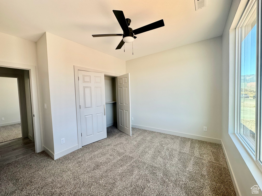 Unfurnished bedroom with carpet floors, a closet, multiple windows, and ceiling fan