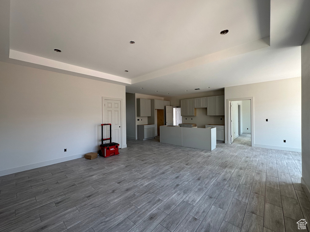 Unfurnished living room featuring a raised ceiling and wood-type flooring