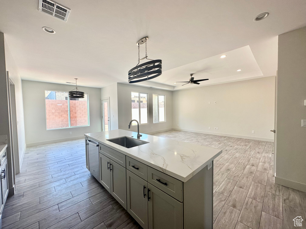 Kitchen with light hardwood / wood-style flooring, an island with sink, sink, and stainless steel dishwasher