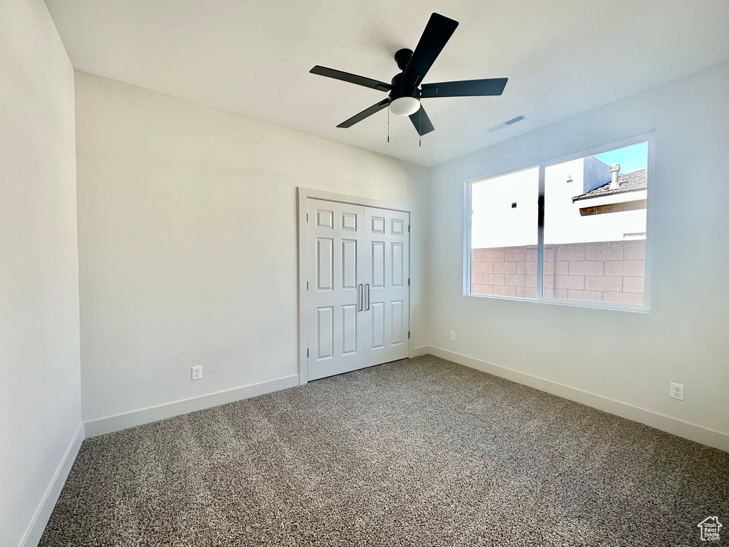 Unfurnished bedroom featuring a closet, carpet, and ceiling fan