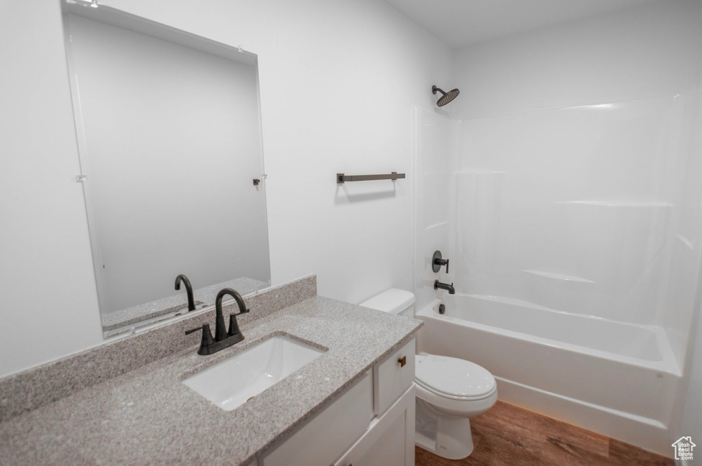 Full bathroom featuring vanity, toilet, hardwood / wood-style flooring, and  shower combination