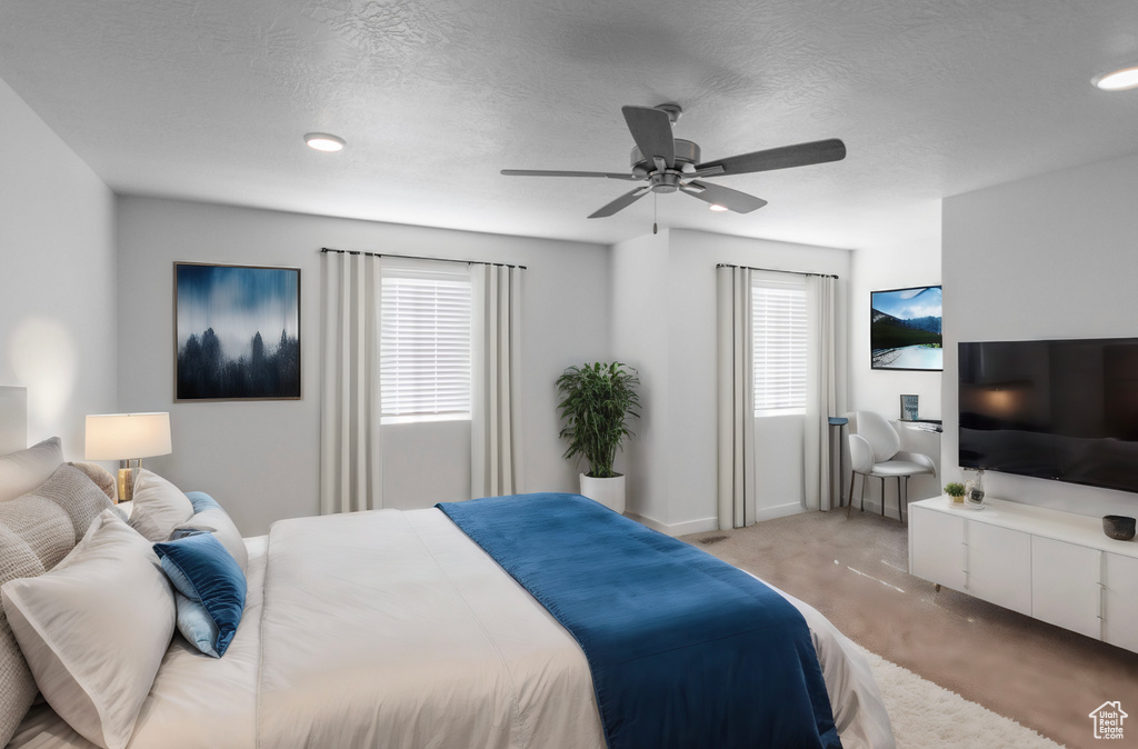 Bedroom with a textured ceiling, ceiling fan, light carpet, and multiple windows