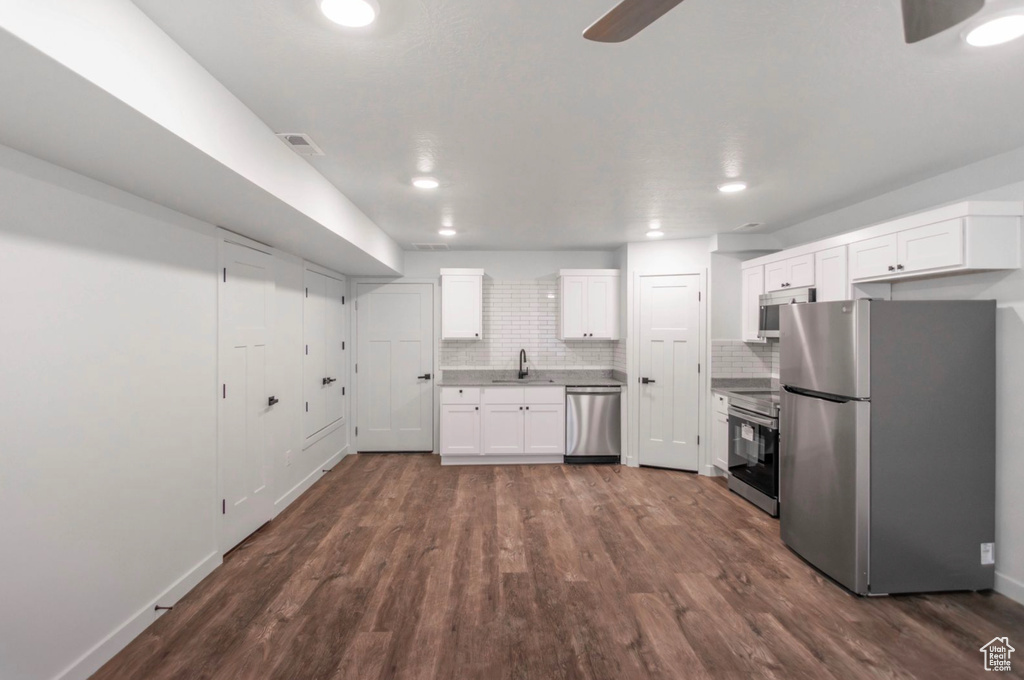 Kitchen with white cabinets, appliances with stainless steel finishes, sink, dark wood-type flooring, and ceiling fan