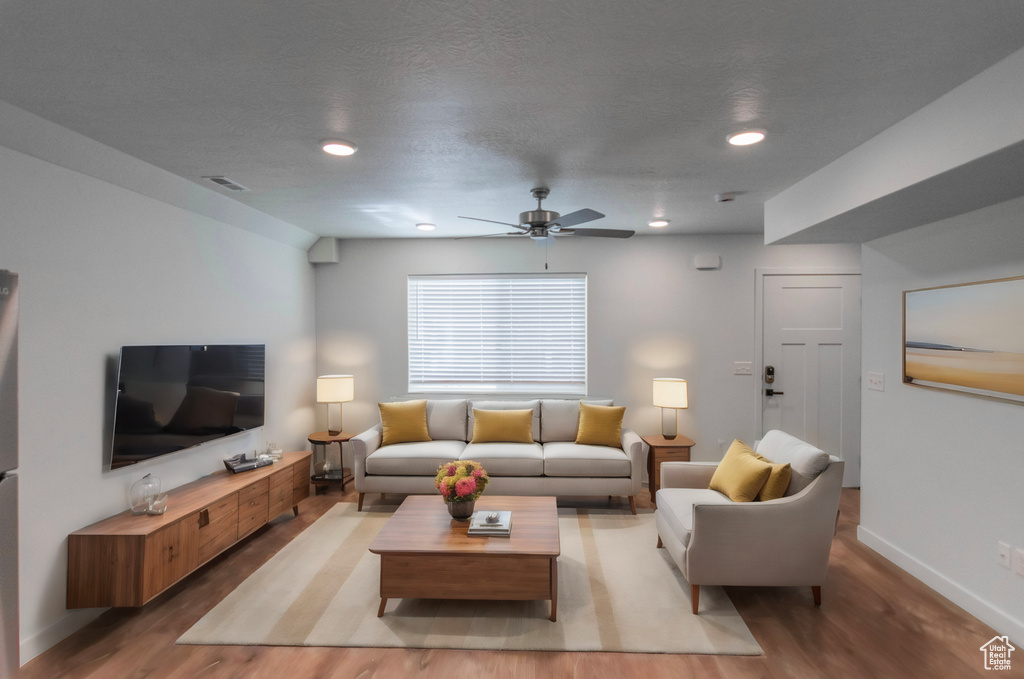 Living room featuring a textured ceiling, ceiling fan, and light hardwood / wood-style floors