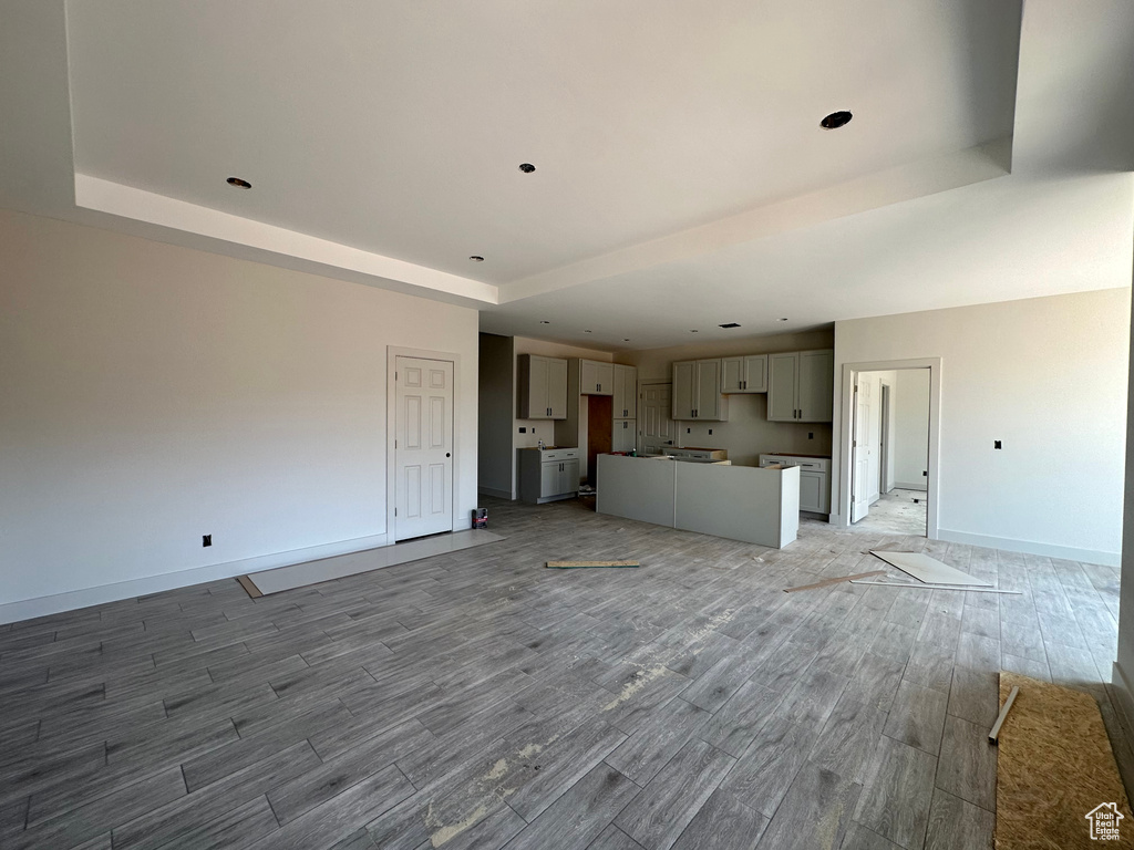 Unfurnished living room with a tray ceiling and hardwood / wood-style flooring